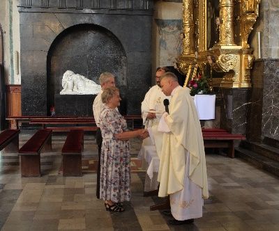zdjęcie przedstawia parę, która w kościele otrzymała pamiątki od księdza