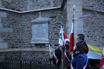 Na zdjęciu widać tablicę upamiętniającą księdza Aleksandra Malanowicza, a przed nią stoą poczty sztandarowe.