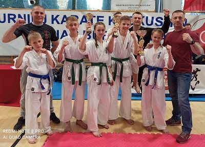 Zdjęcie przedstawia zawodników z UKS KK „MUSHIN” Szydłowiec z pucharami za zdobyte miejsca. Obok nich stoi trener, sensei Robert Wyciszkiewicz.